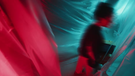 asian girl in retro tracksuit wandering around dark studio with neon light
