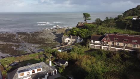 aerial drone orbit shot of an english mill house on the shoreline of a coastal village - lee bay, beach, ilfracombe, devon, england