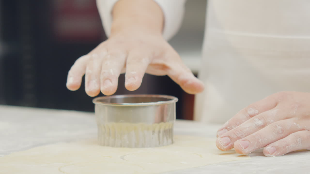 Chef's hands shaping and cutting the ravioli dough using artisanal techniques in a professional kitchen