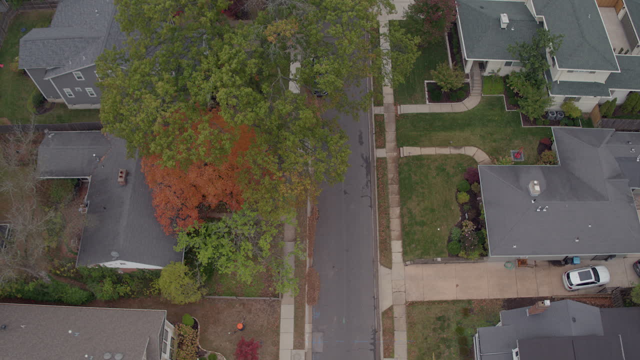 elevación aérea sobre una calle suburbana y casas en un barrio agradable en un día de otoño