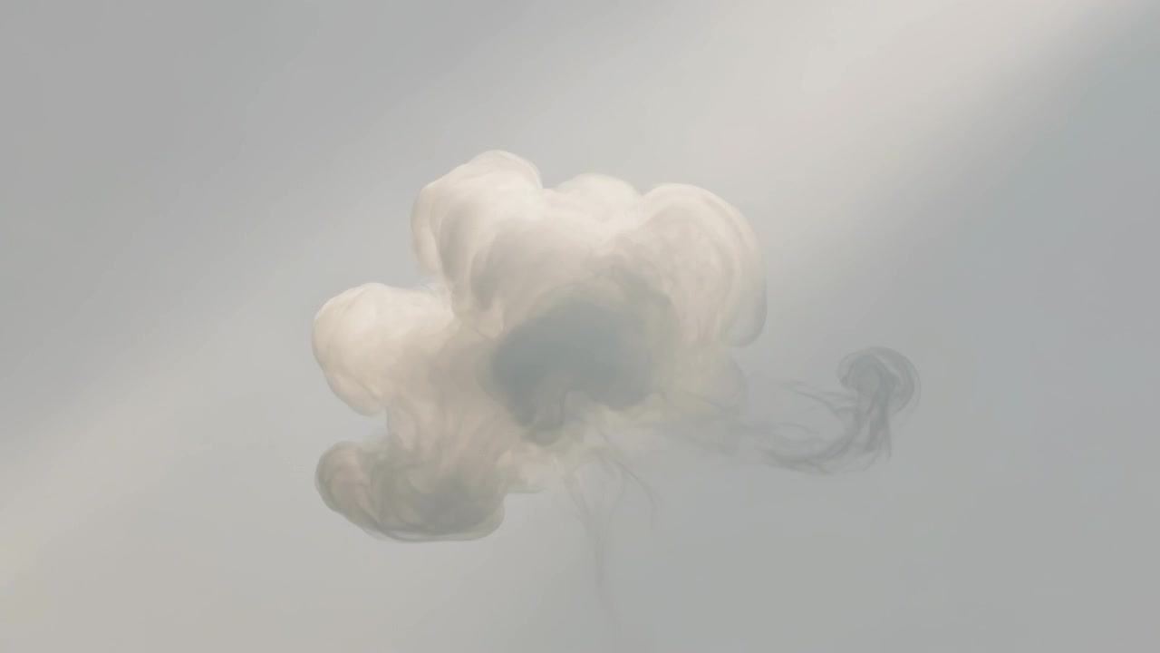 Formazione di un singolo pennacchio bianco simile a una nuvola che si espande e si sposta verso destra in una vasca da studio con luce obliqua.
