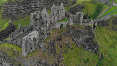 tilted top down drone view flying over medieval castle ruins on the edge of a basalt outcropping near the atlantic ocean