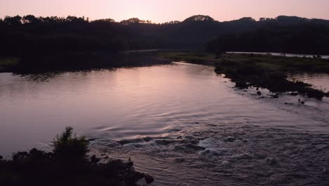 beautiful river flowing through countryside wilderness at sunset, aerial view