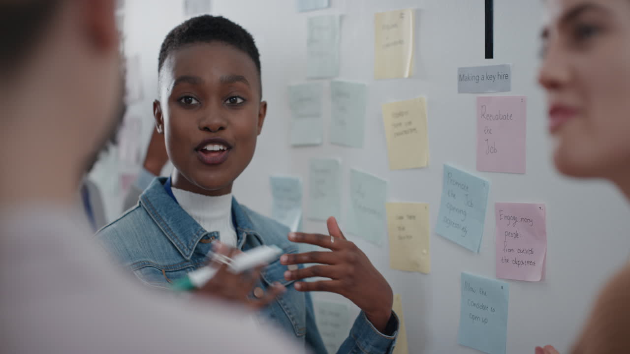 african american business woman using sticky notes brainstorming with colleagues in meeting team leader sharing creative problem solving ideas for solution enjoying teamwork in startup office