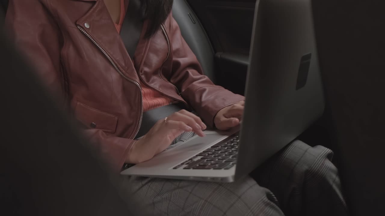 한 여성이 차 안에서 노트북을 사용하고 있습니다. 은 공간에도 불구하고 집중적이고 생산적입니다.