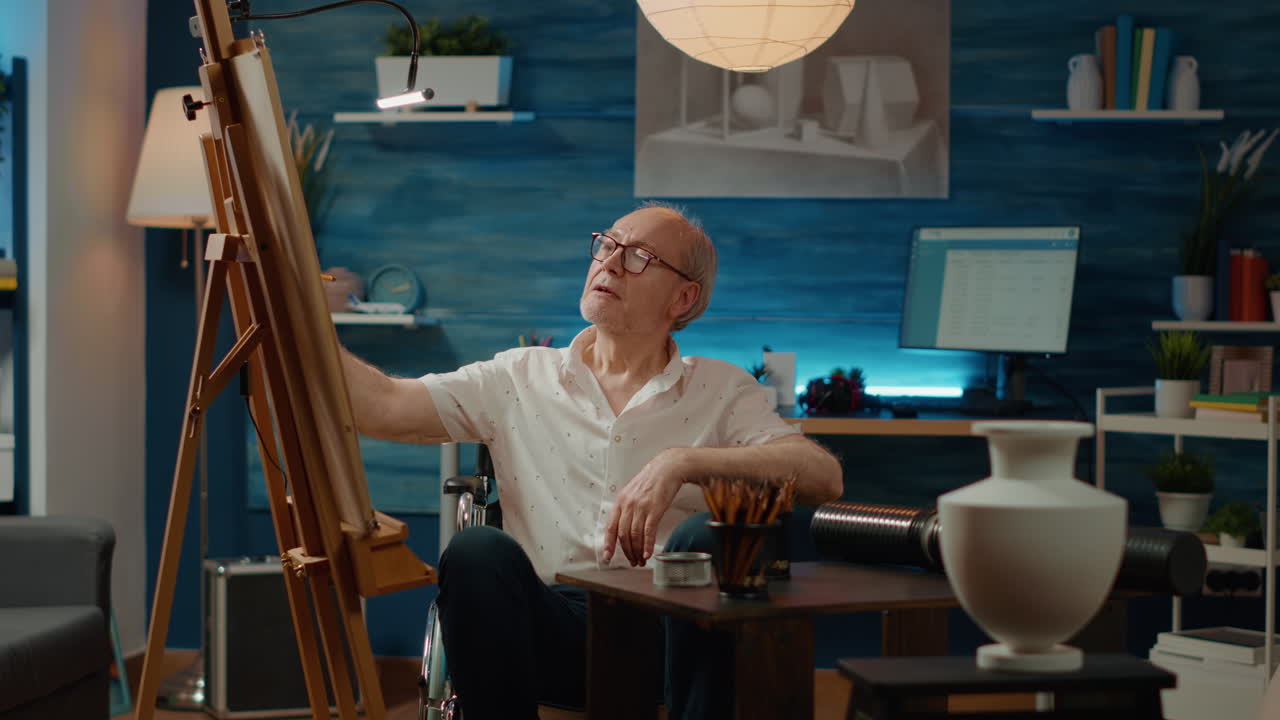 Retired man with chronic disability drawing masterpiece on canvas