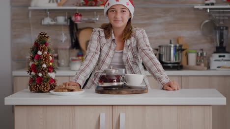 Portrait-of-child-looking-into-camera-standing-at-table-with-baked-cookies-and-infused-tea