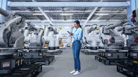 mujer en una fábrica moderna con brazos robóticos