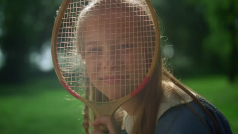 Chica-Alegre-Haciendo-Muecas-Con-Raqueta-De-Bádminton-En-El-Primer-Plano-Del-Parque-De-Verano.