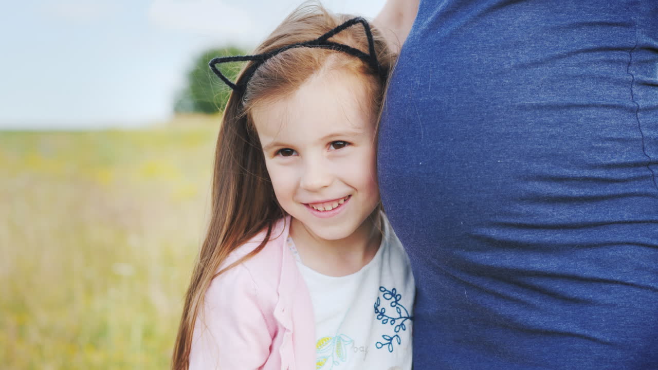 두 번째 아이를 기다리는 임신한 어머니의 뱃속에 있는 귀여운 소녀의 초상화