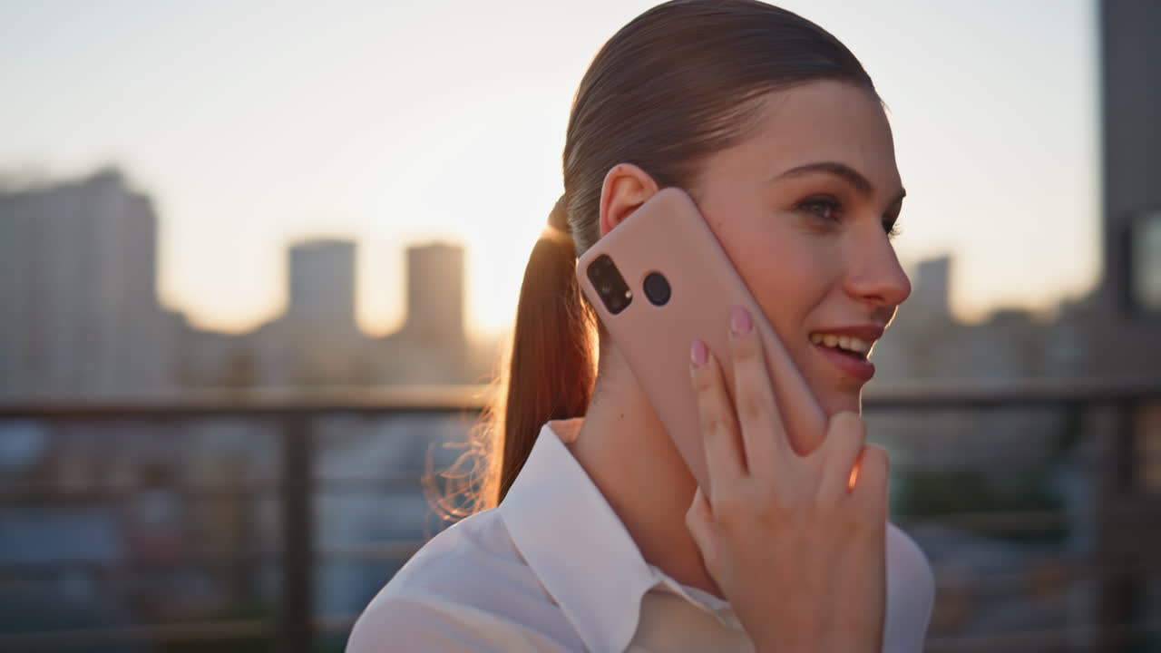 Smiling woman calling mobile phone at sunset balcony closeup. Happy lady talking