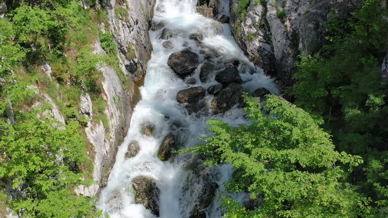 Medium wide angle aerial drone shot of water flowing over rocky shelf of boka waterfall spring during the day