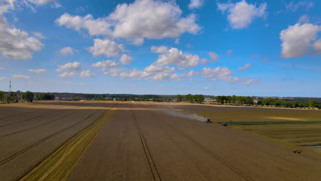 Una-Maquinaria-Agrícola-Cosechando-Cultivos-En-Un-Vasto-Campo-En-Puck,-Polonia-En-Un-Día-De-Verano---Dron-Aéreo---Plano-General