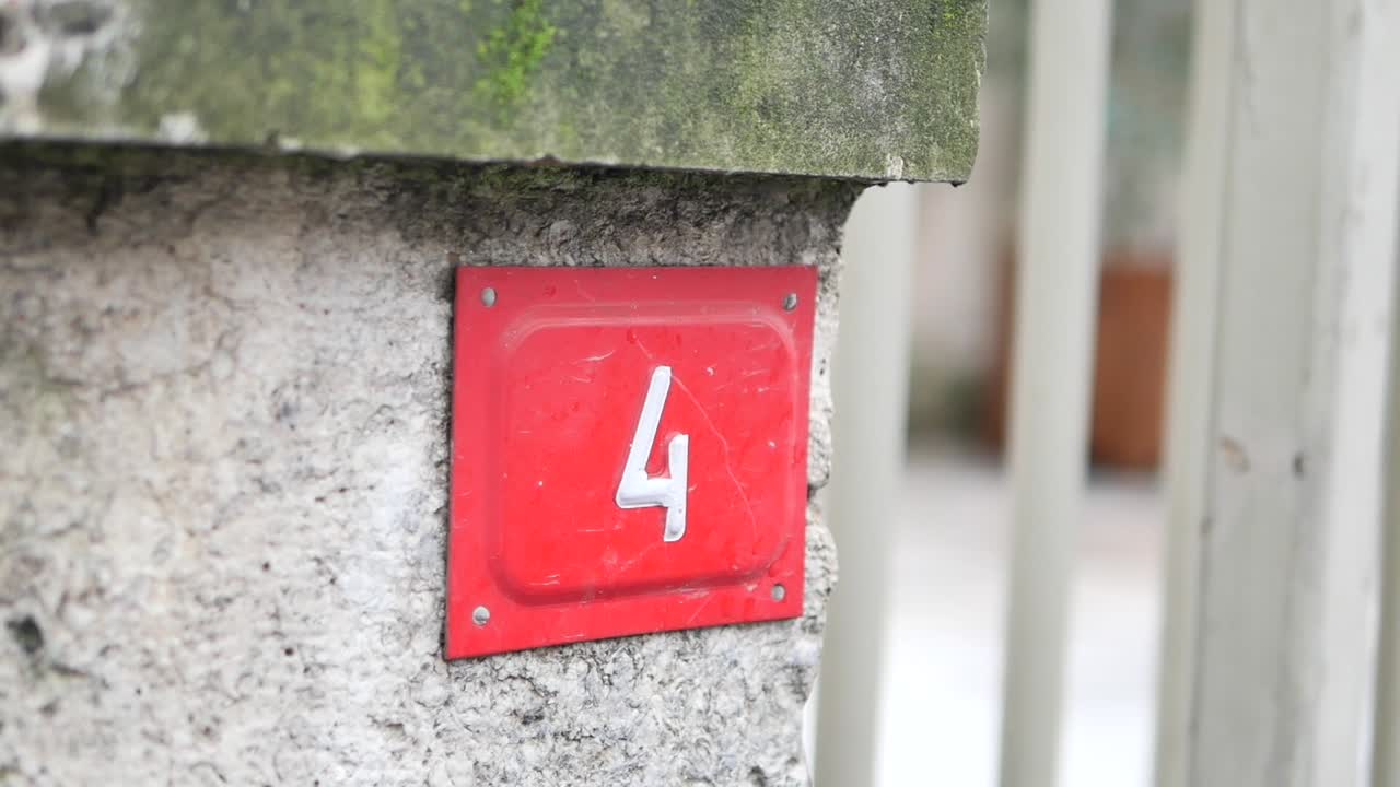 Placa vermelha com o número 4 em uma parede de pedra