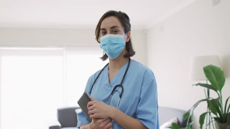 retrato de uma médica caucasiana usando máscara facial em casa