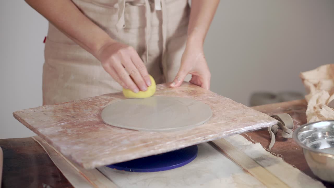 Woman shaping a clay plate on a pottery wheel