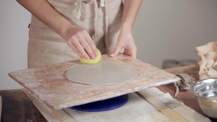 Woman shaping a clay plate on a pottery wheel