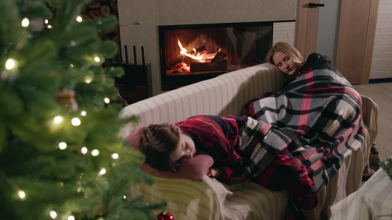 People sleeping by fireplace near Christmas tree