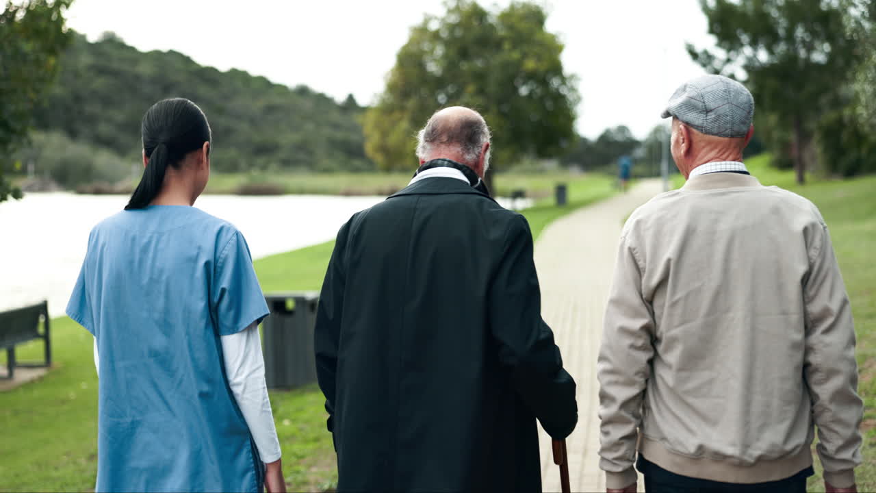 Elderly people walking with a nurse in a park
