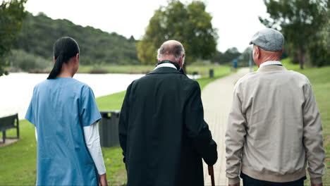 elderly people walking with a nurse in a park