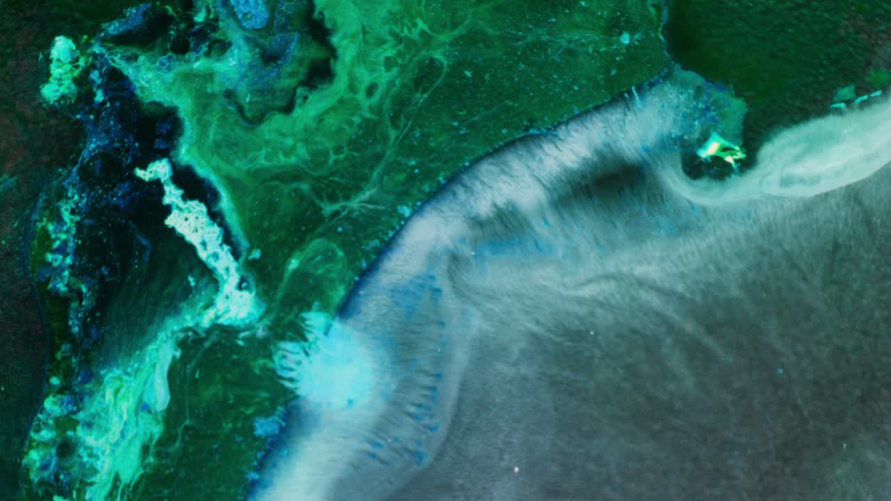 Flowing alcohol ink creates an abstract scene in green, blue, and white tones