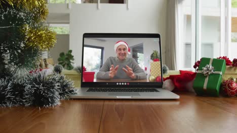 Smiling-caucasian-man-wearing-santa-hat-on-christmas-video-call-on-laptop