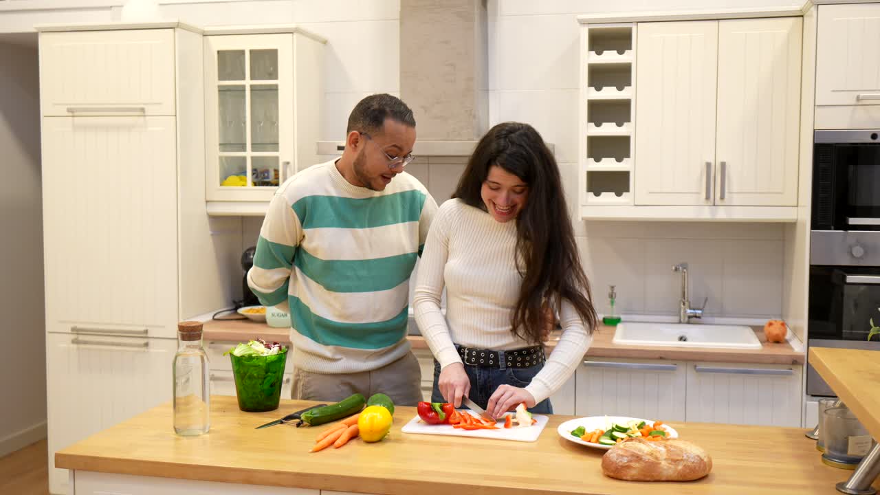 Casal feliz picando vegetais juntos em uma cozinha moderna.