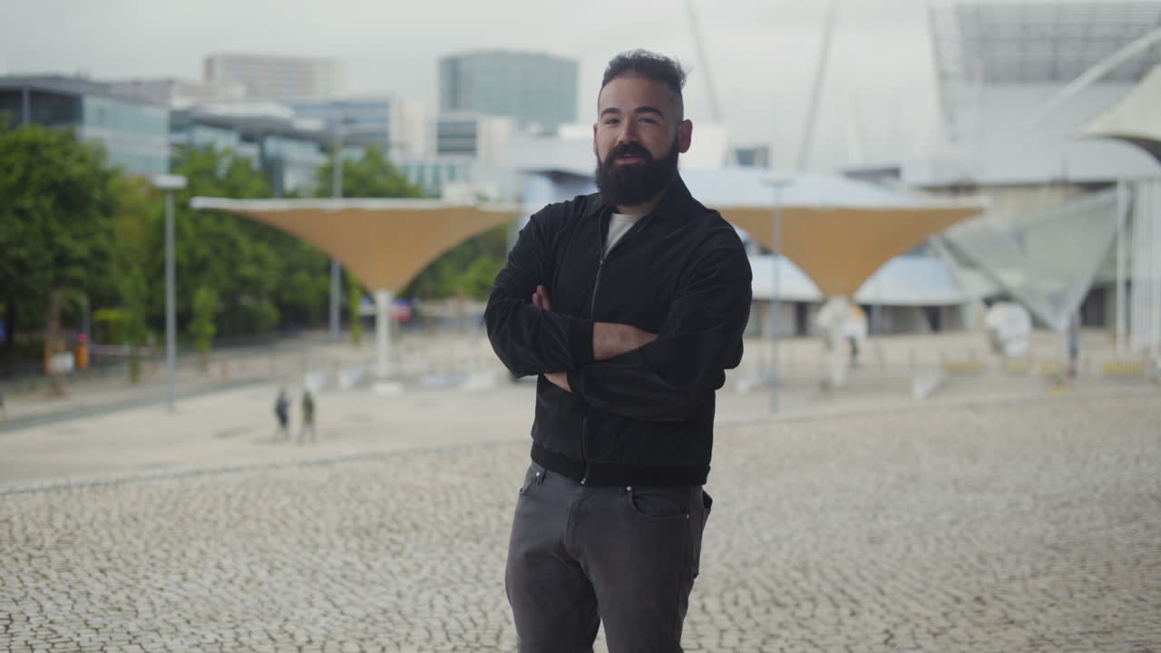 joven confiado de pie en la plaza con los brazos cruzados