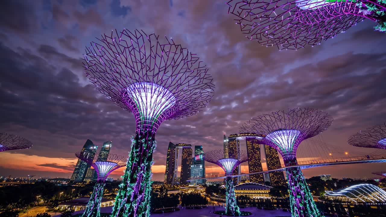 Video aereo cattura un paesaggio urbano futuristico con architettura iconica e vegetazione lussureggiante.