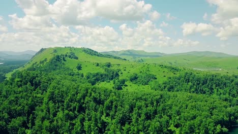 aerial flying over mountains and forest under a cloudy sky also in sight is the mountain river