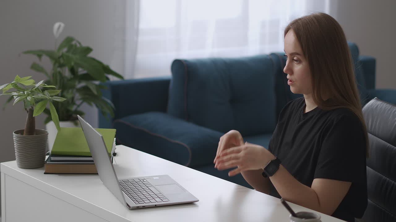 online communicating by video chat woman is talking to web camera of laptop sitting in living room home office for remote work