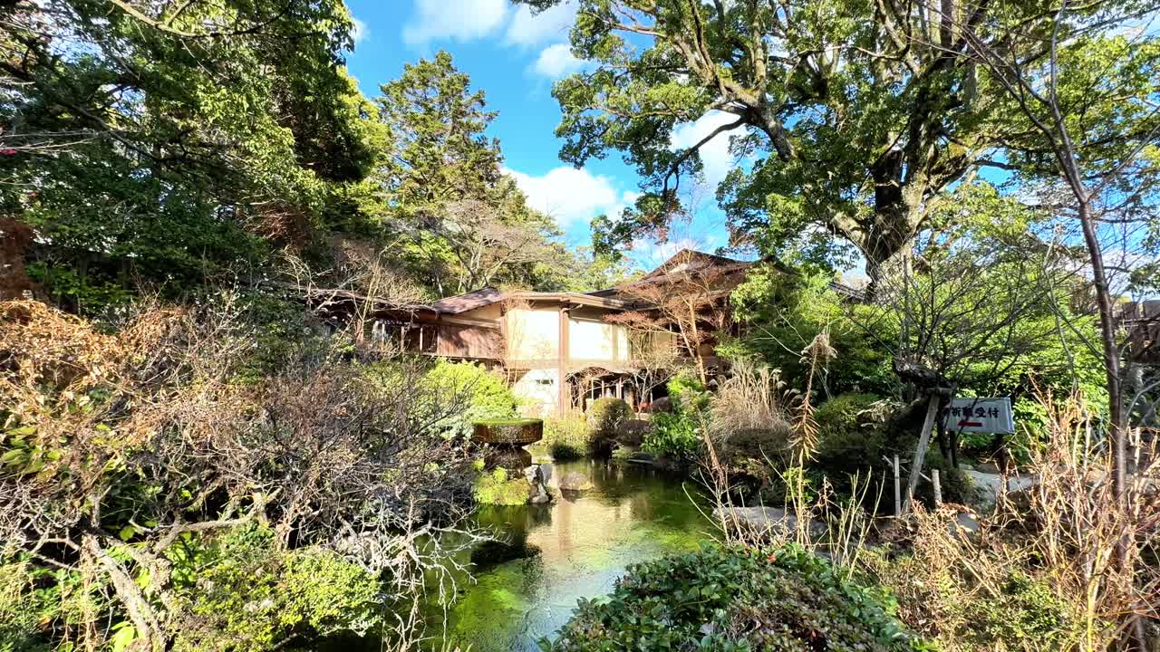 Sereno giardino del Castello di Odawara con alberi rigogliosi e uno stagno tranquillo