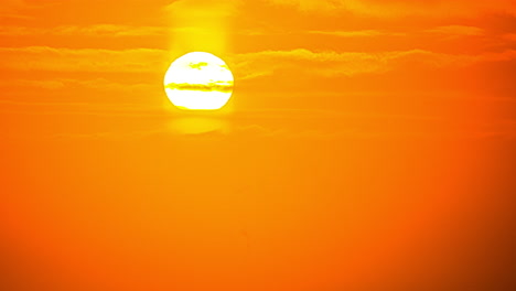 amazing timelapse of golden setting sun moving behind fluffy clouds moving softly in the sky and the sun shining through the clouds with beautiful rays