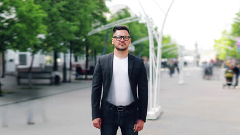 man in a black suit and white shirt standing on a city street