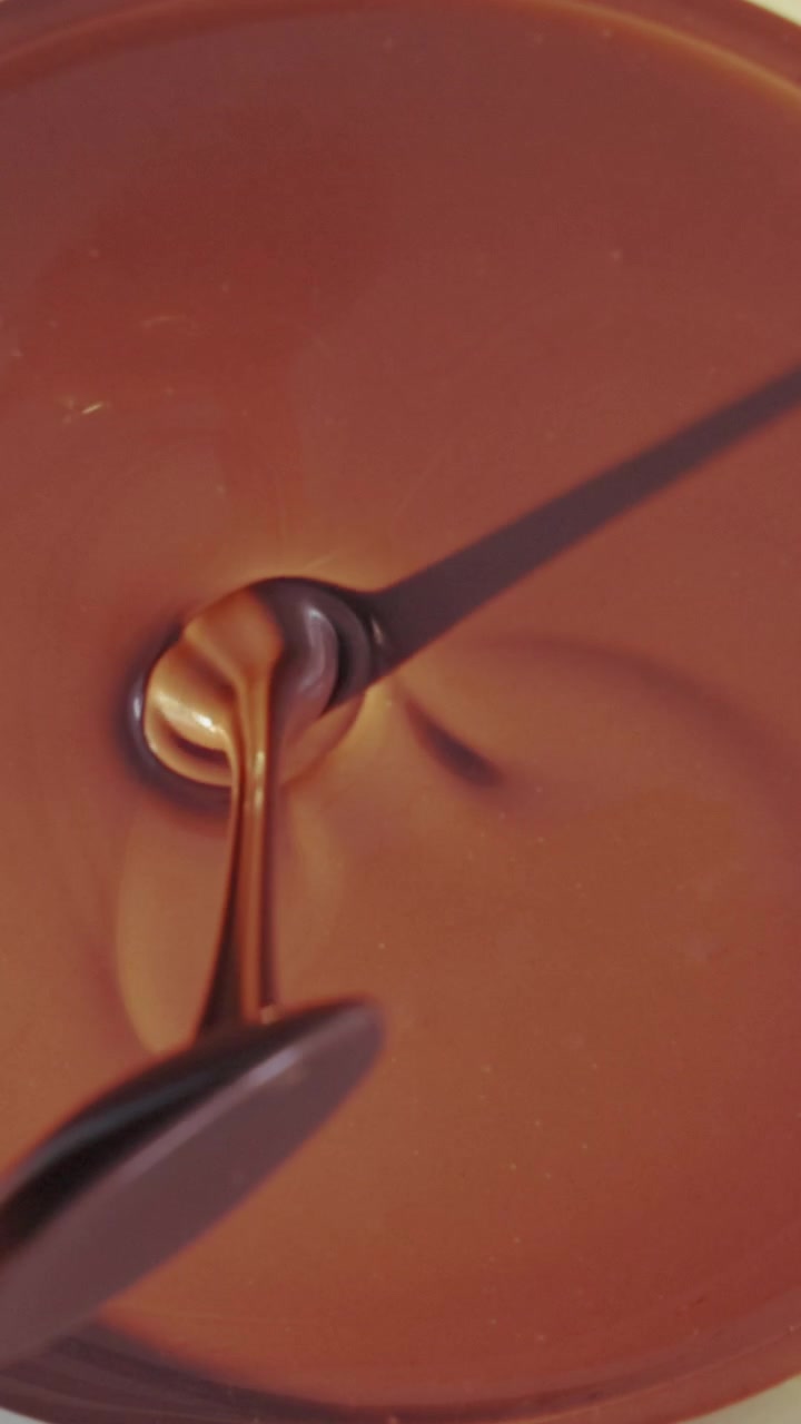 Cucchiaio che mescola cioccolato fondente fuso e liscio in una ciotola