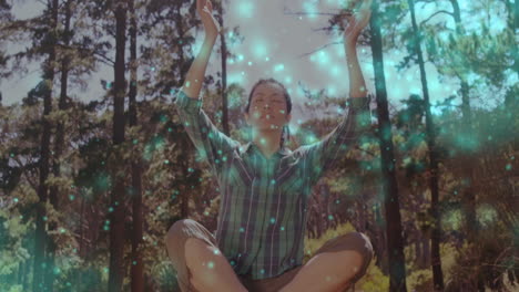 animation of light spots over asian woman meditating in forest