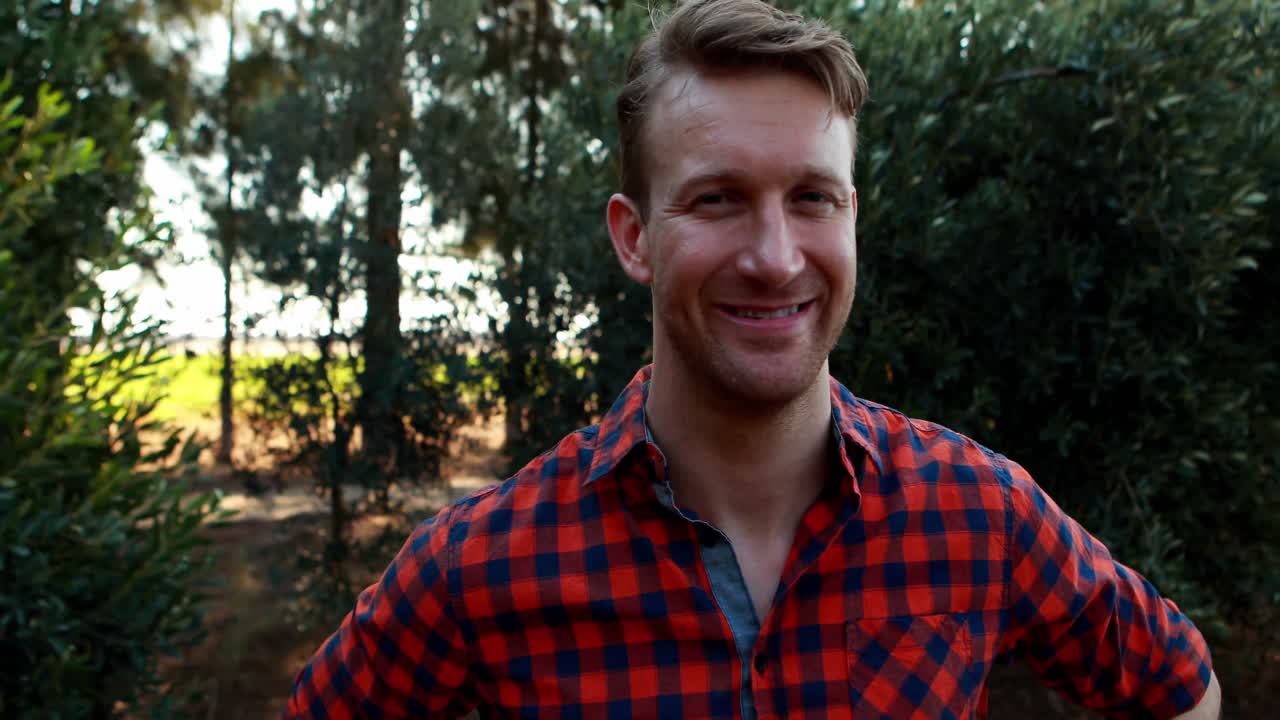 Smiling man standing with hand on hip in olive farm