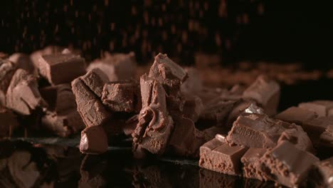 polvo de cacao fino cayendo a cámara lenta sobre chispas de chocolate negro