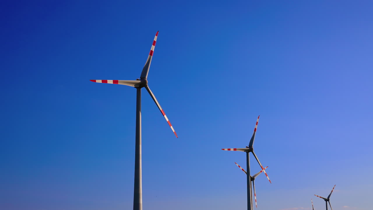 Turbines spin under blue skies. Wind turbines spin actively against a vibrant blue sky on a sunny day, harnessing wind energy efficiently