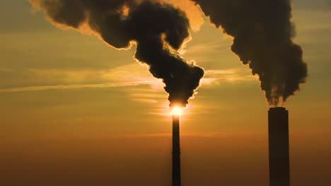 air pollution. clouds of smoke coming from the chimneys of the plant with beautiful golden yellow lighting of setting sun. drone flying over smoking smokestacks of a steel factory.