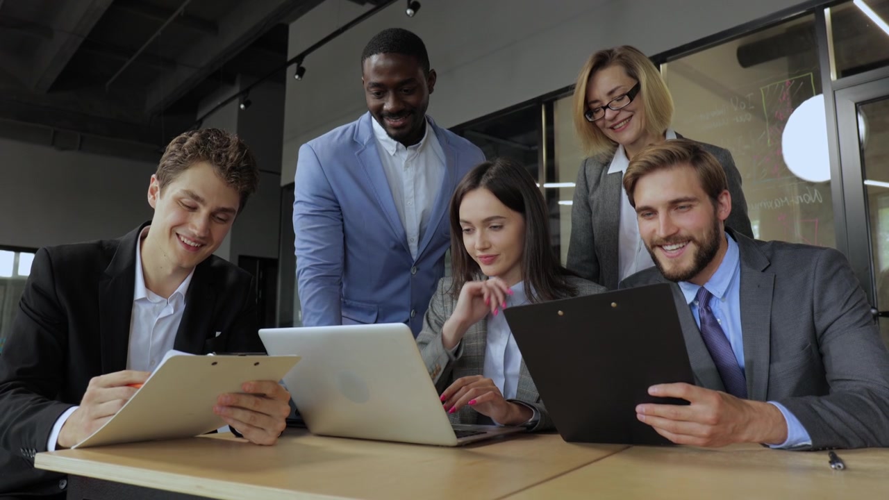 Team aziendale diversificato che collabora al laptop durante una riunione in un ufficio moderno