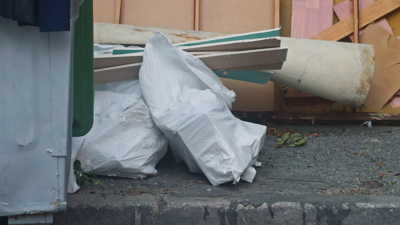 Abandoned construction materials, wood, furniture and filled bags near a dumpster in Sofia, Bulgaria