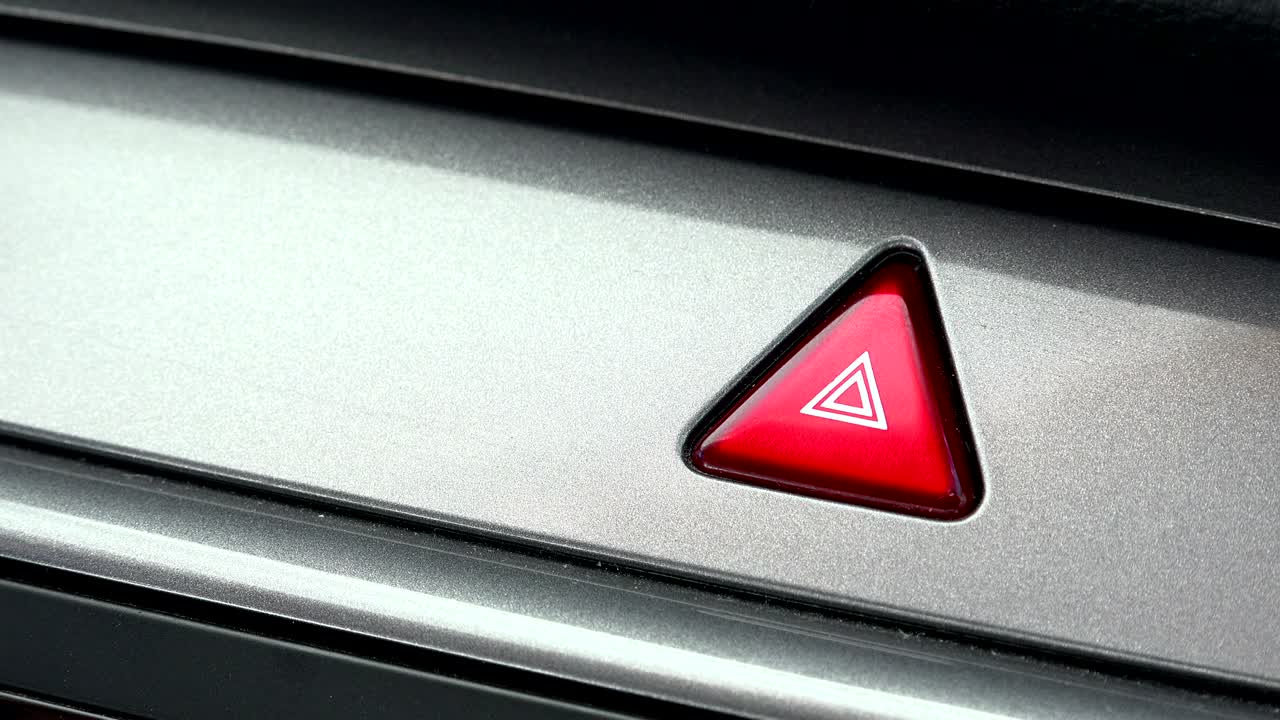 dedo golpeando el botón de luz de emergencia del coche