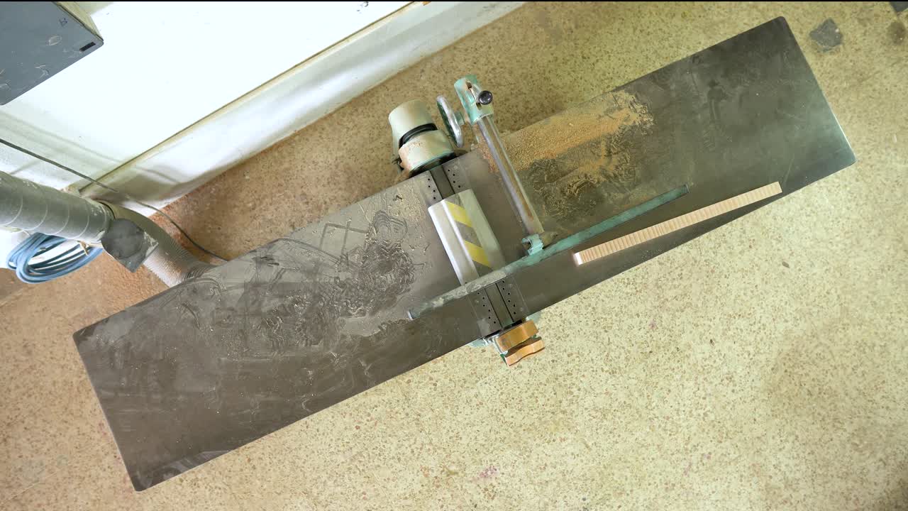 A carpenter uses a woodworking machine to process wood in a workshop
