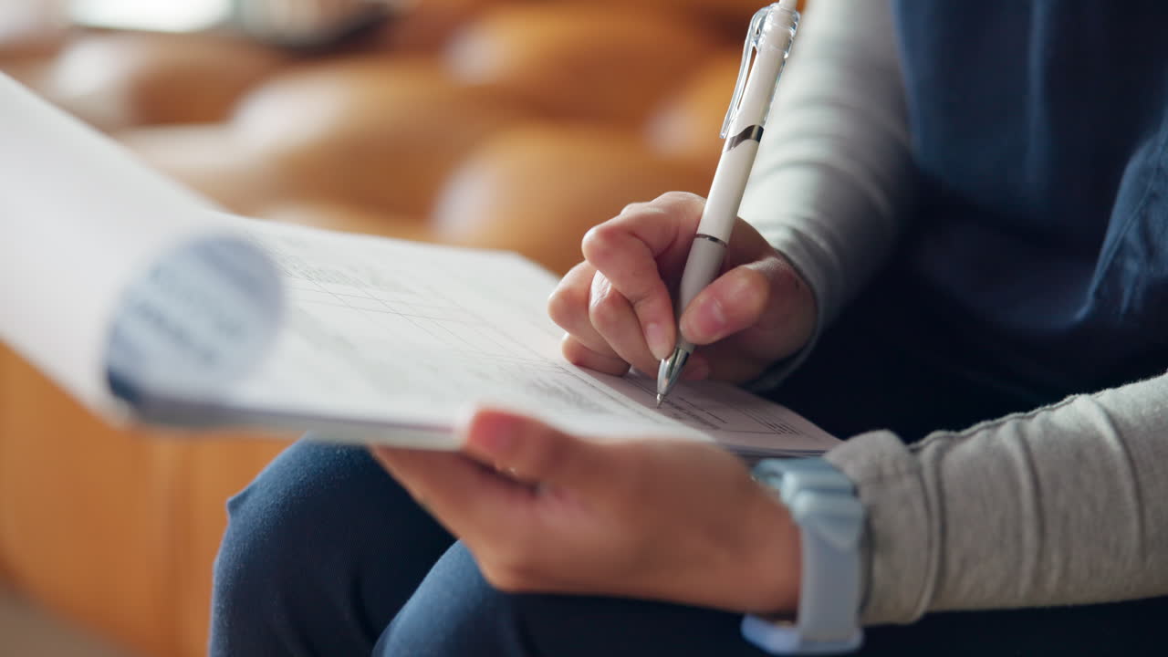 Close Up of Person's Hands Writing on a Document with a Pen