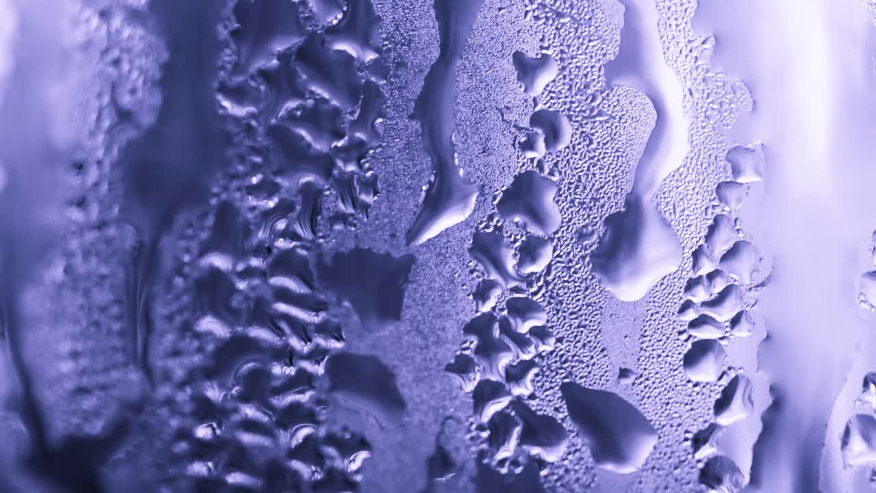 Close-up view of intricate condensation patterns forming on a glass surface, showcasing texture and detail.