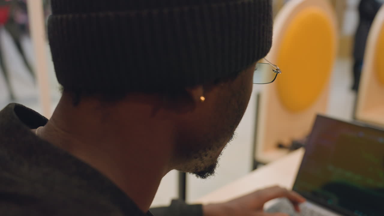 Close-up van een ijverig werkende programmeur. Stedelijke caféomgeving met een aandachtige ontwikkelaar aan het werk. Rustige stadscafésetting toont een ontwikkelaar die verdiept is in softwareprobleemoplossing en -ontwikkeling.