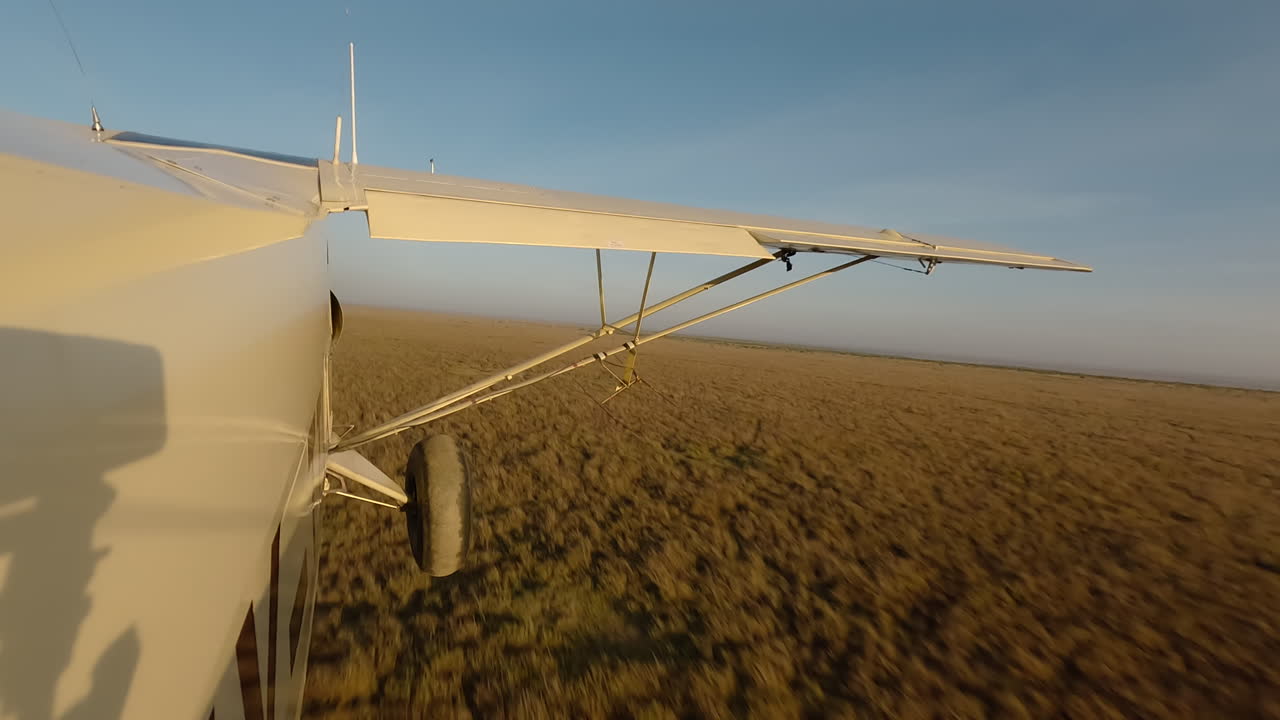 Kleines Flugzeug von der Seite über einer trockenen Gras-Savanne.