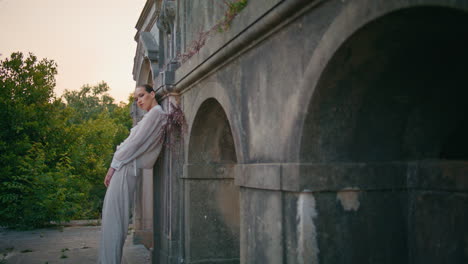 modelo de moda posando hermoso palacio abandonado zoom en. mujer inclinada pared de piedra