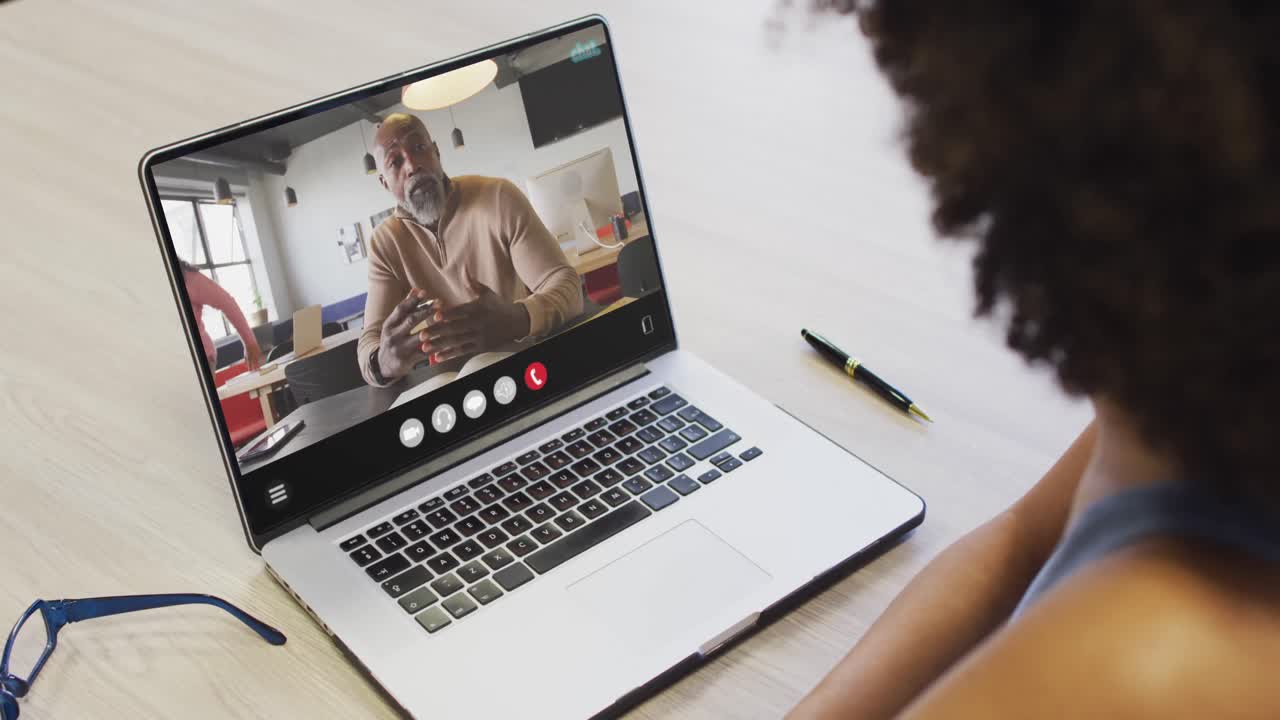 African american woman using laptop for video call, with business colleague on screen